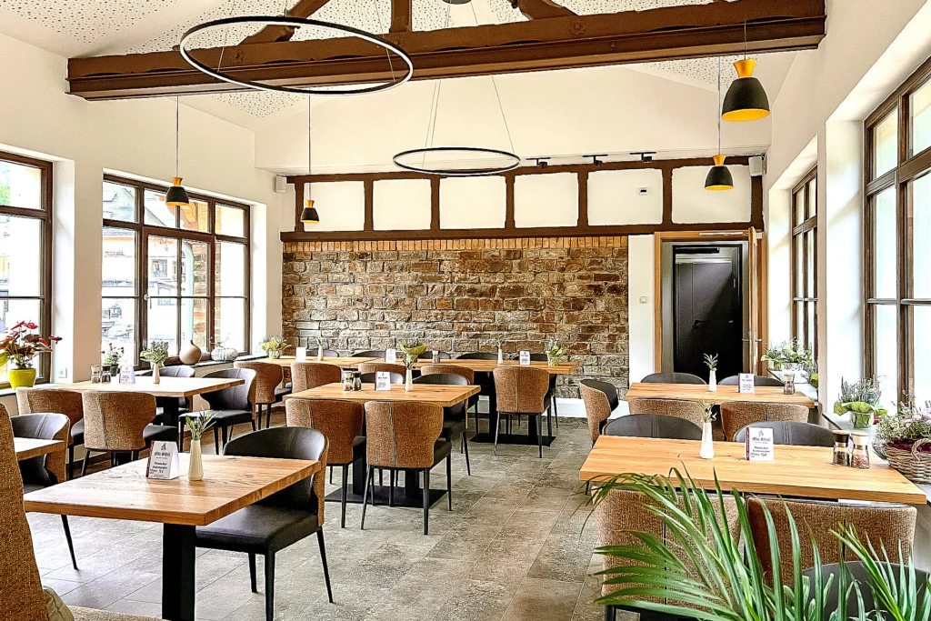 Innenansicht der Taverna Sirtaki mit Bruchsteinwand, Holztischen und bequemer Bestuhlung.