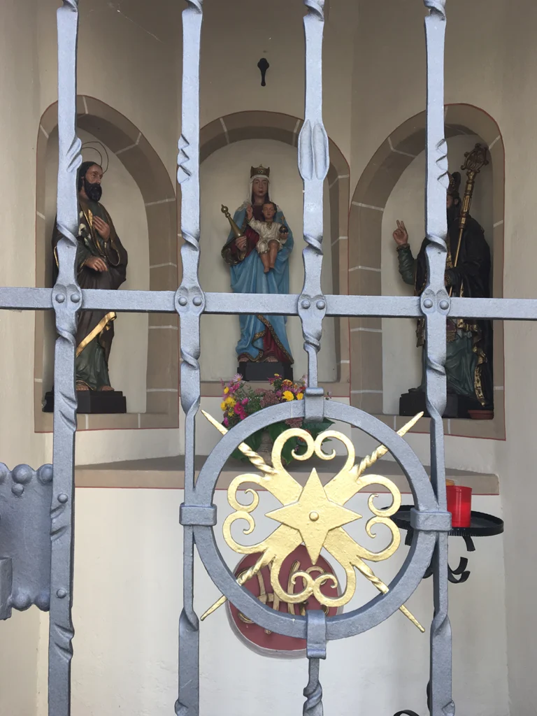 Blick durch das Gitte der Nikolaus Kapelle am Rossberg auf die Heiligenfiguren.